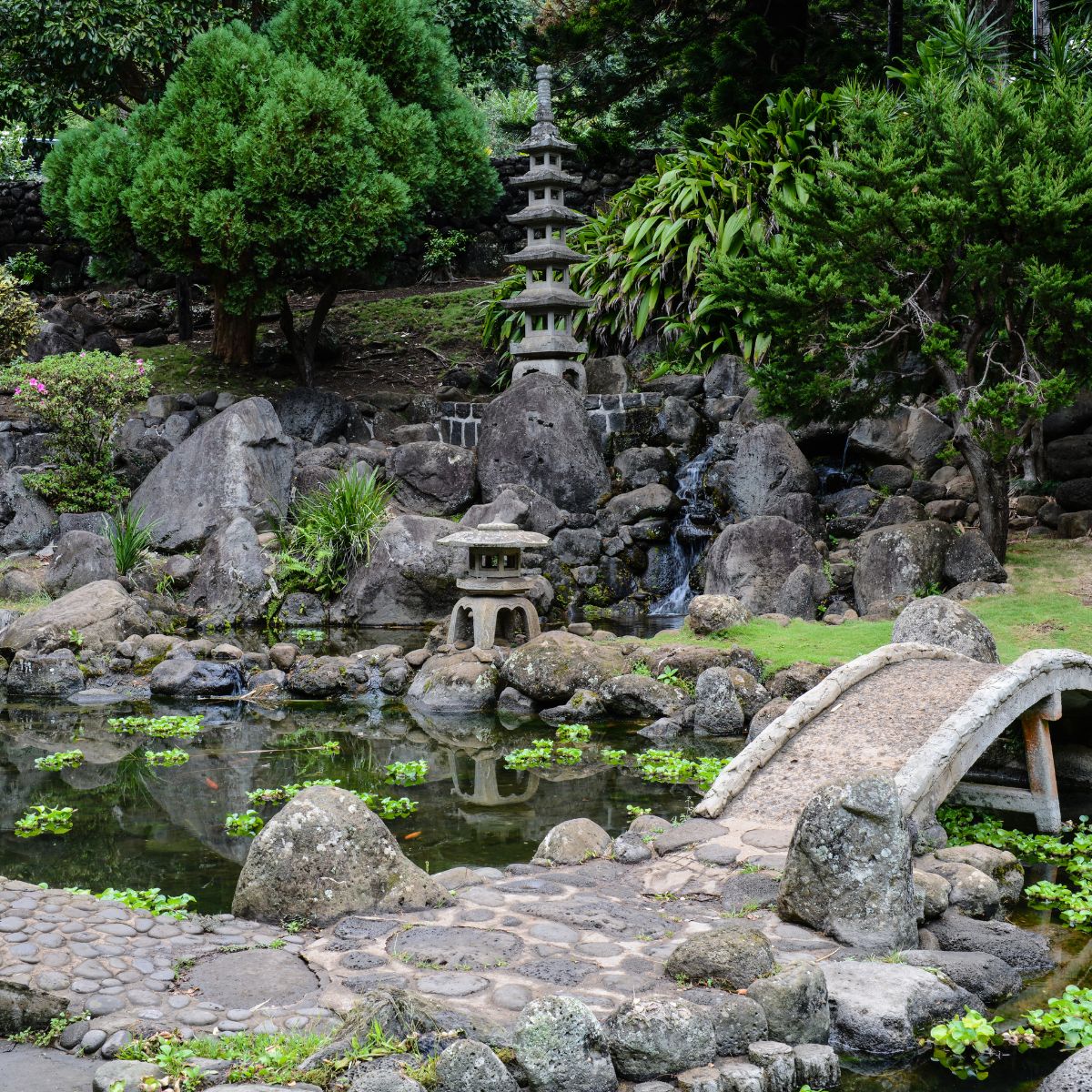 Asian style garden with lots of rocks, a pond and a stone bridge.