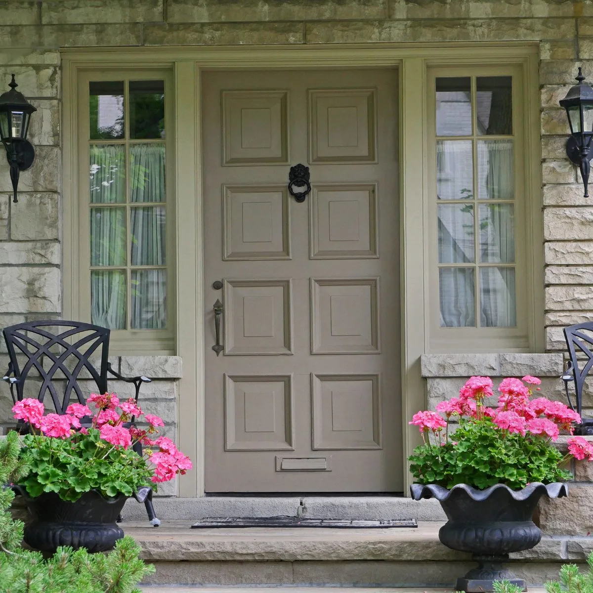 pink potted geraniums in front of the house door.