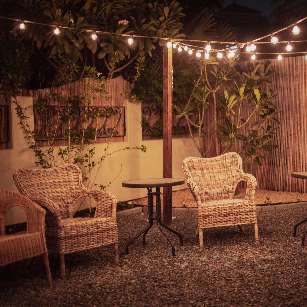 A simple backyard gathering place with two wicker chairs and a small round table. 