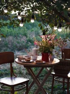A small romantic spot in the backyard with a table set in the dim lights.