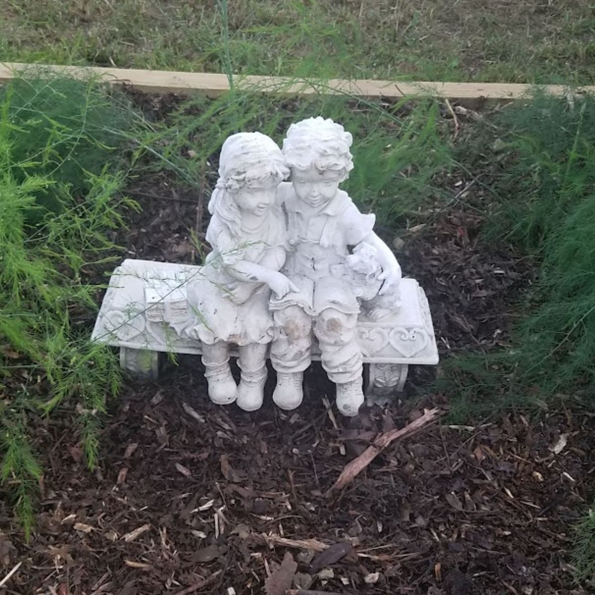 A cute statue of a boy and girl sitting on a bench.