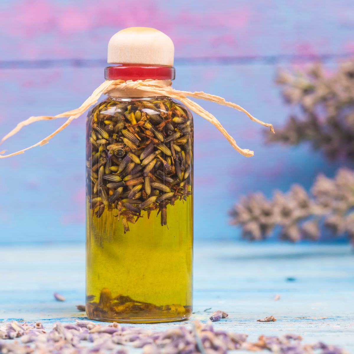 Lavender buds being infused in a glass bottle with olive oil.