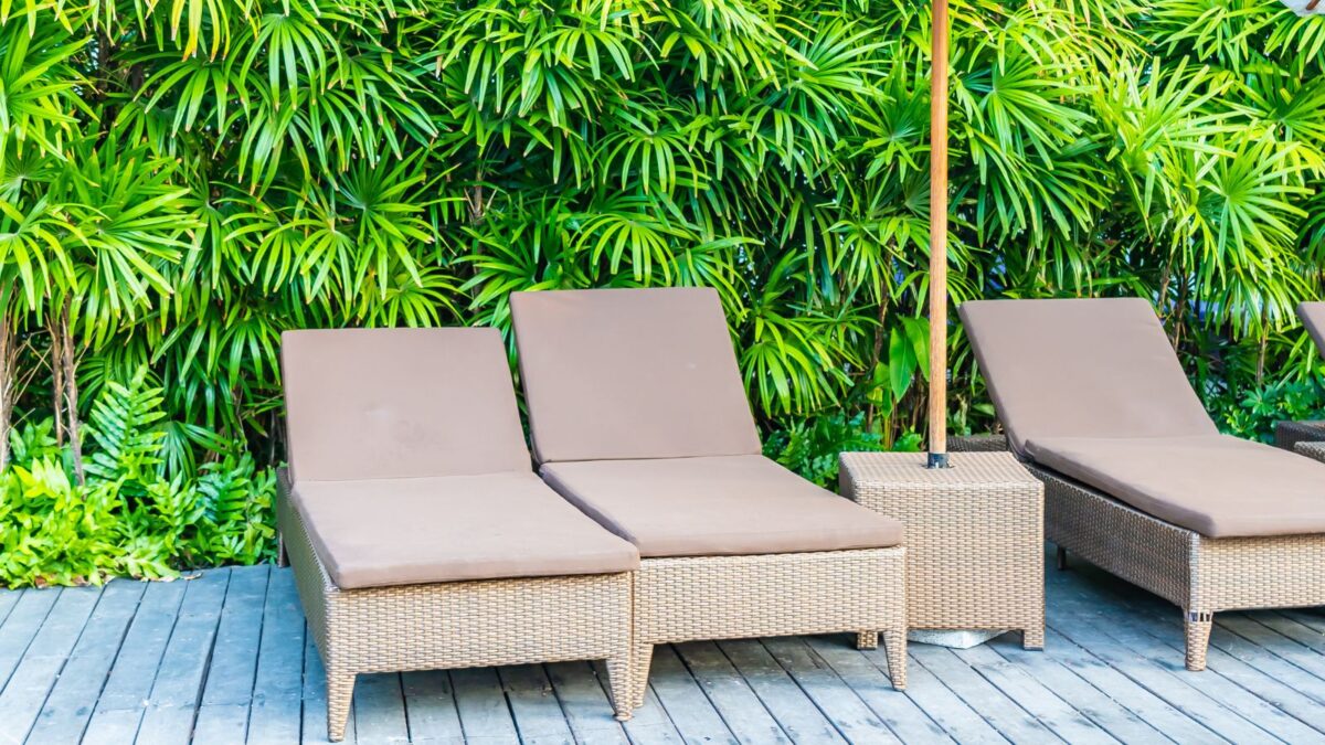 Outdoor chairs and an umbrella stand on a wooden deck. 