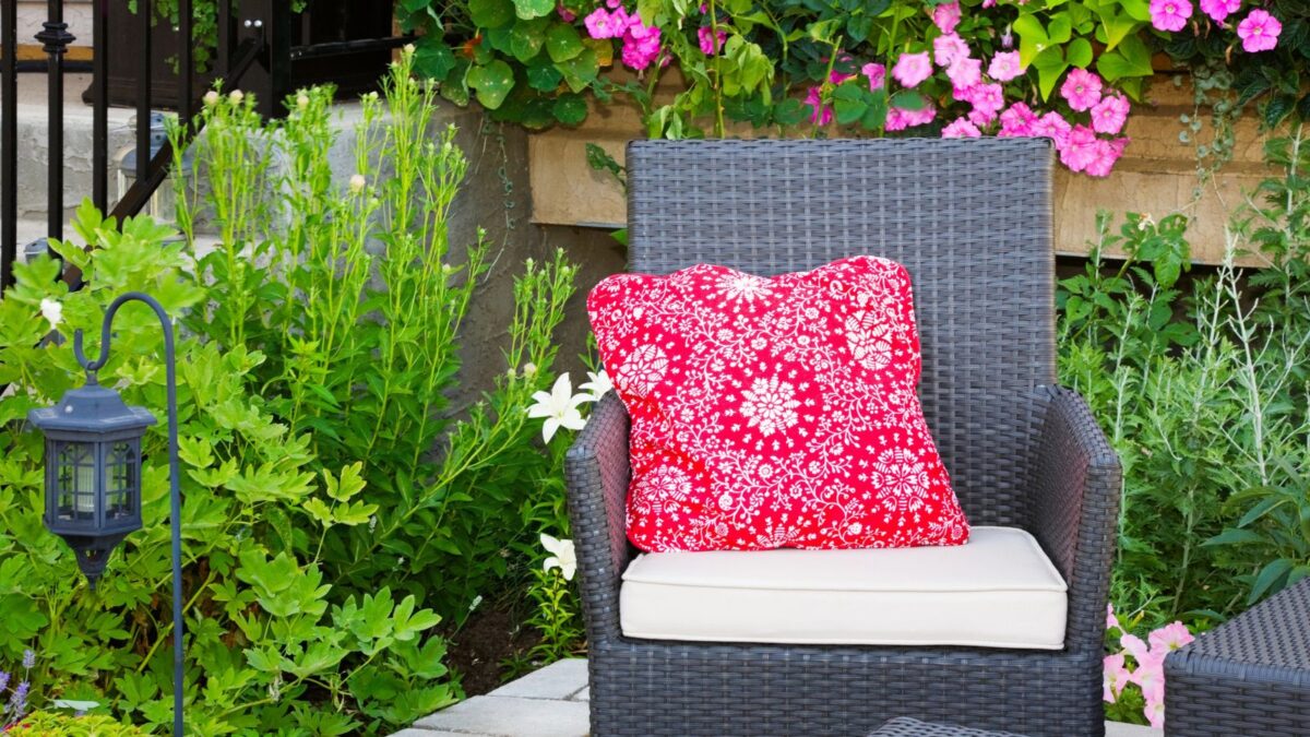 relaxing backyard spot with a cozy chair and a red colored pillow.  