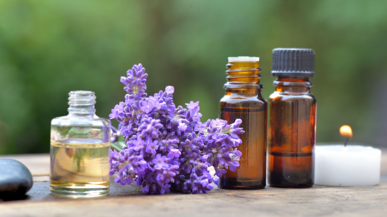 bottles of essential oil among lavender flower arranged on a wooden table in garden
