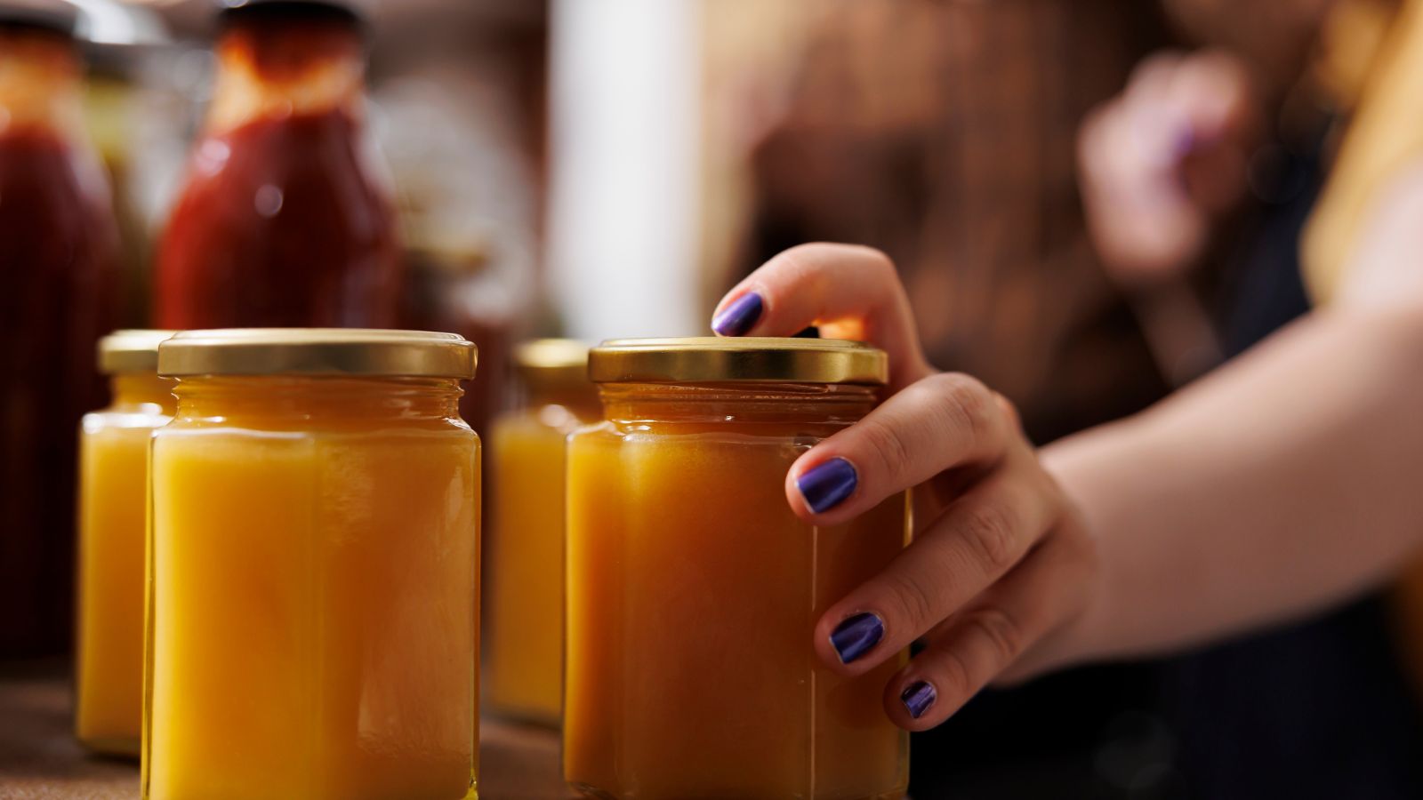 woman's hand on a honey jar.