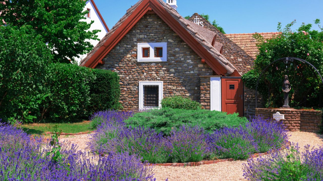 Dreamy stone cottage house in a traditional mediterranean village with a garden full of ornamental lavender flowers and a statue, Tihany Hungary