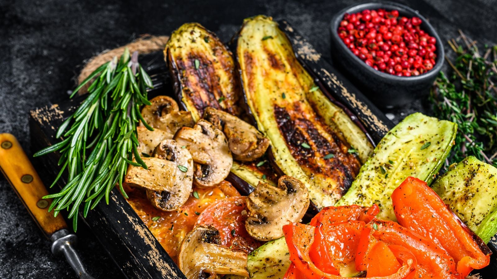 grilled vegetables bell pepper, zucchini, eggplant and tomato in a wooden tray.