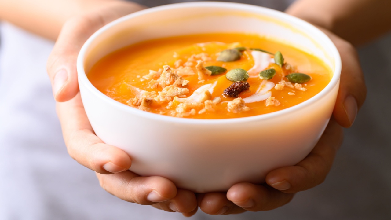 Butternut squash pumpkin soup in bowl holding by woman hand, Homemade food in autumn season