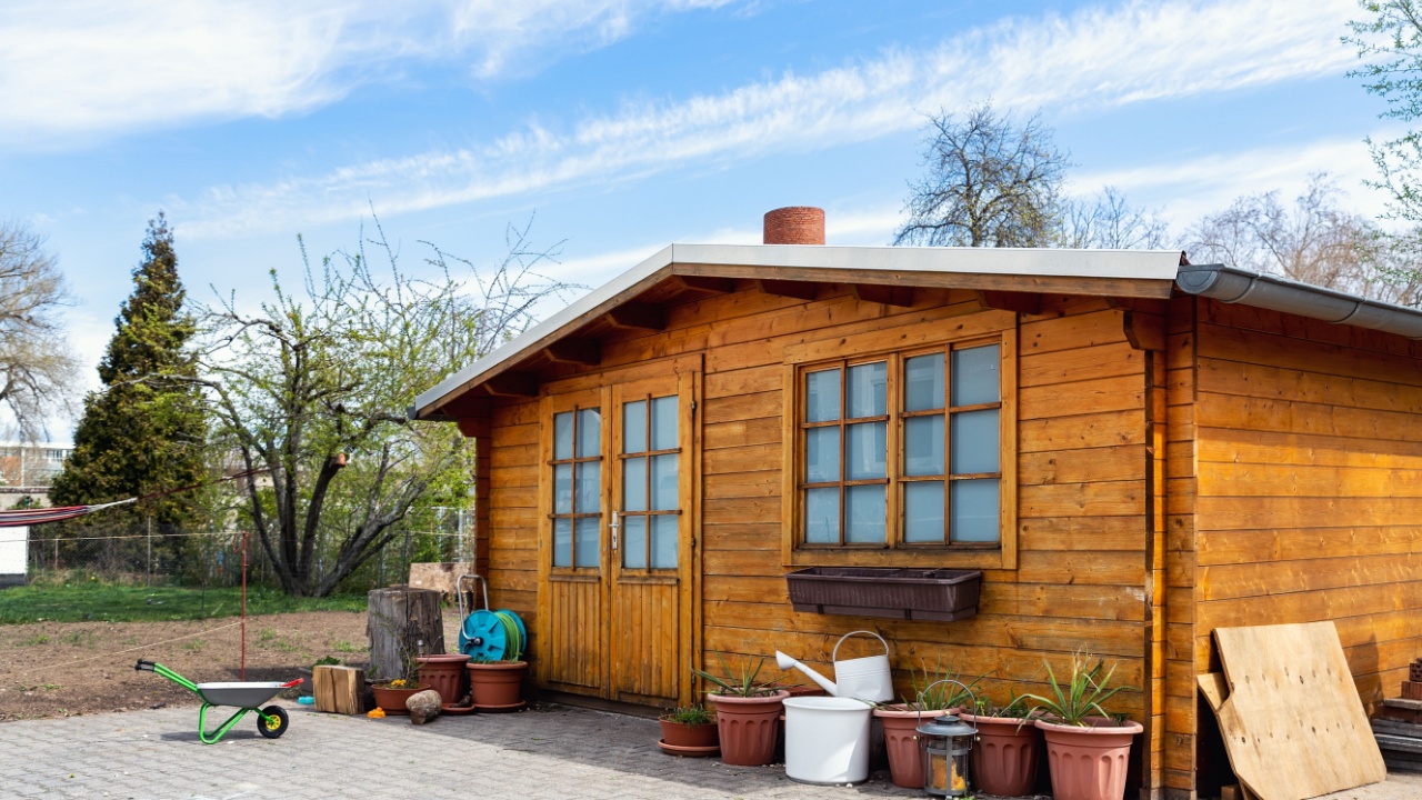 Small beautiful wooden house shed or storage hut for garden tools equipment and bicycles at backyard at beautiful american or european countryside backyard. Cozy rural yard stuff warehouse