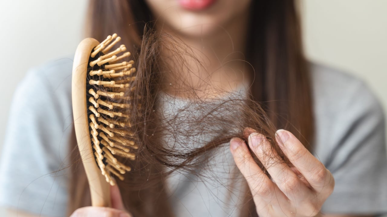 Close-up young woman brushing her hair and have many hair loss on the comb