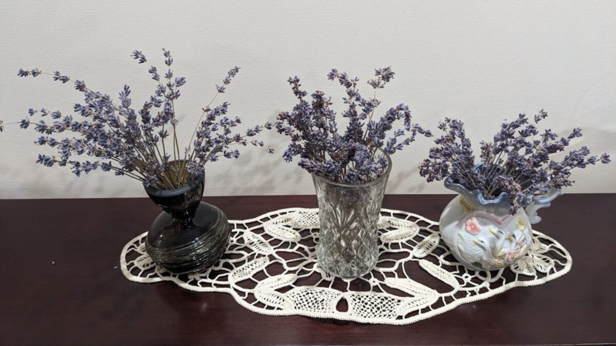 vases with dry lavender displayed on a piano with a doily.