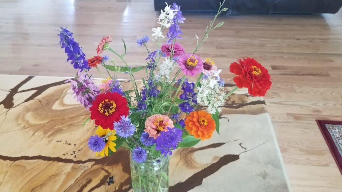 Colorful wildflowers in a glass vase sitting on a granite countertop.