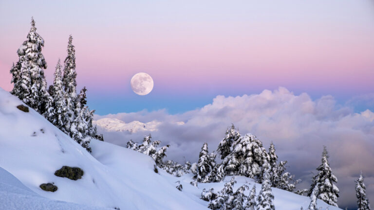 Full moon over snowy mountains landscape in the purple twilight sky