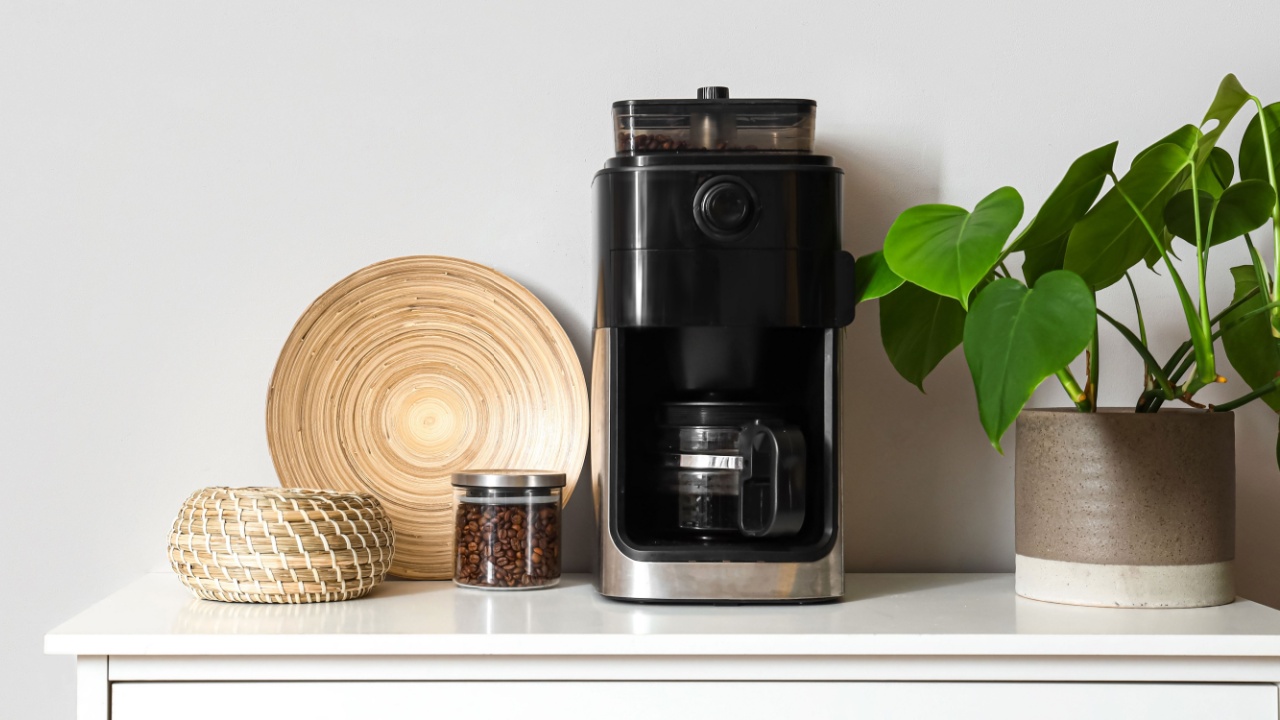 Modern coffee machine and beans on table in room