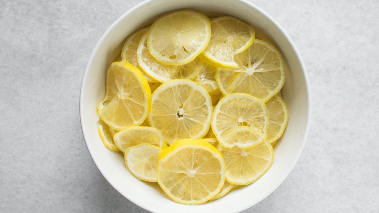 Overhead view of lemon slices in a white bowl, prep for making cocktail garnish and lemon cheong