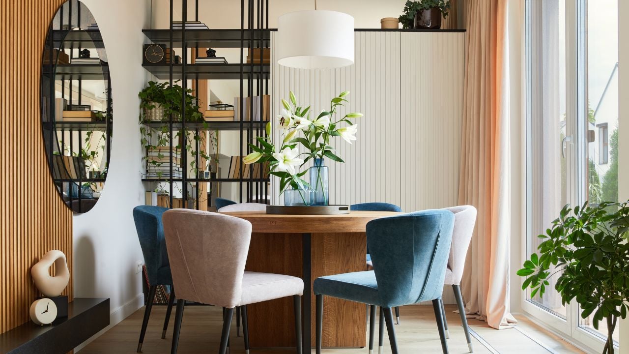 Stylish composition of elegant dining room interior design with velvet armchairs, design rouded wooden table and beautiful personal accessories. Glamour interior design inspiration. Template.