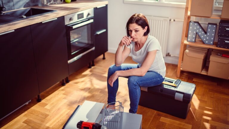 Worried woman sitting on a toolbox during renovating kitchen