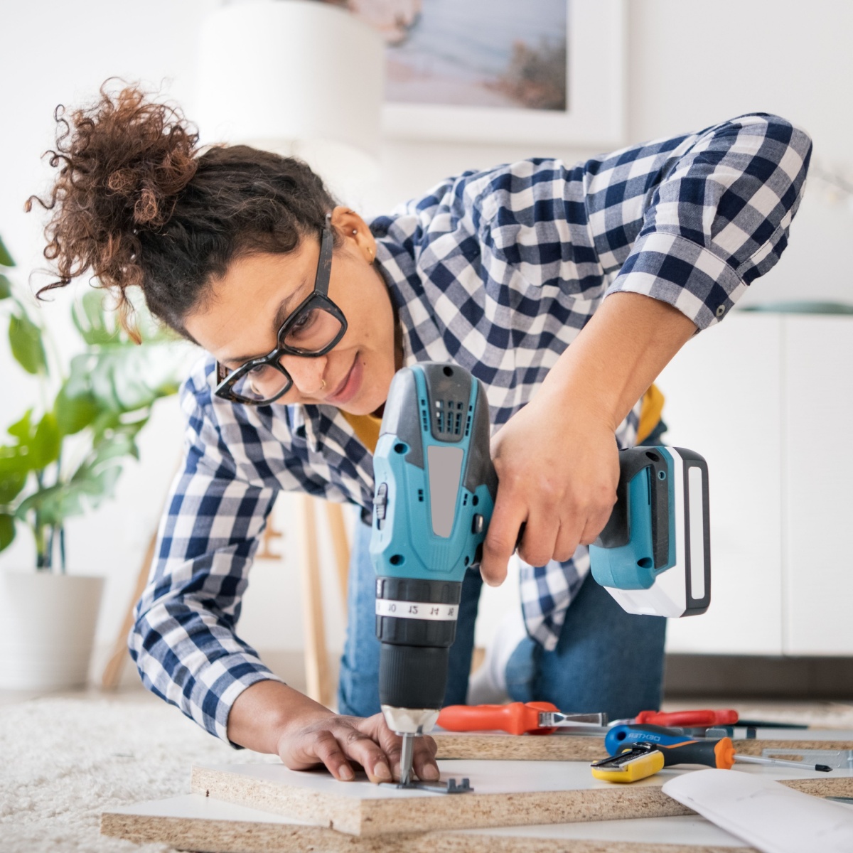 woman holding electric drill tool to assembly furniture in new home