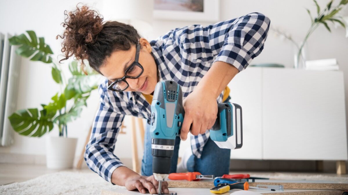 woman holding electric drill tool to assembly furniture in new home