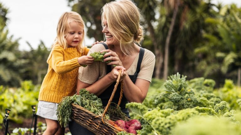 Happy single mother picking fresh vegetables with her daughter