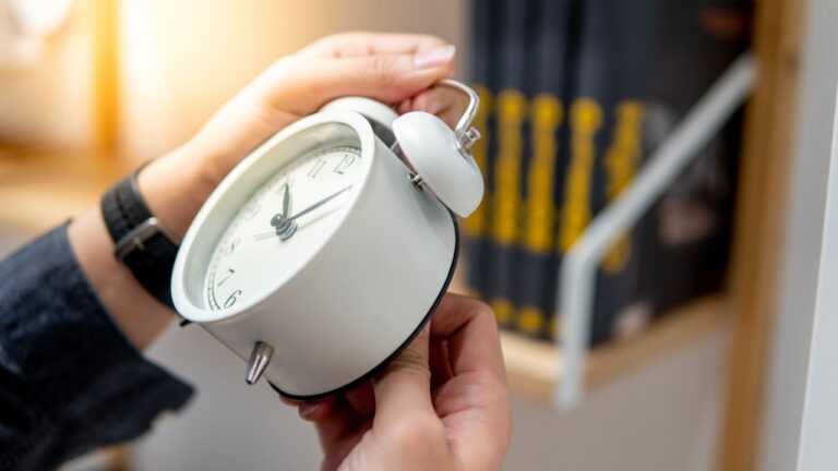 Male hand adjusting or changing the time on white clock