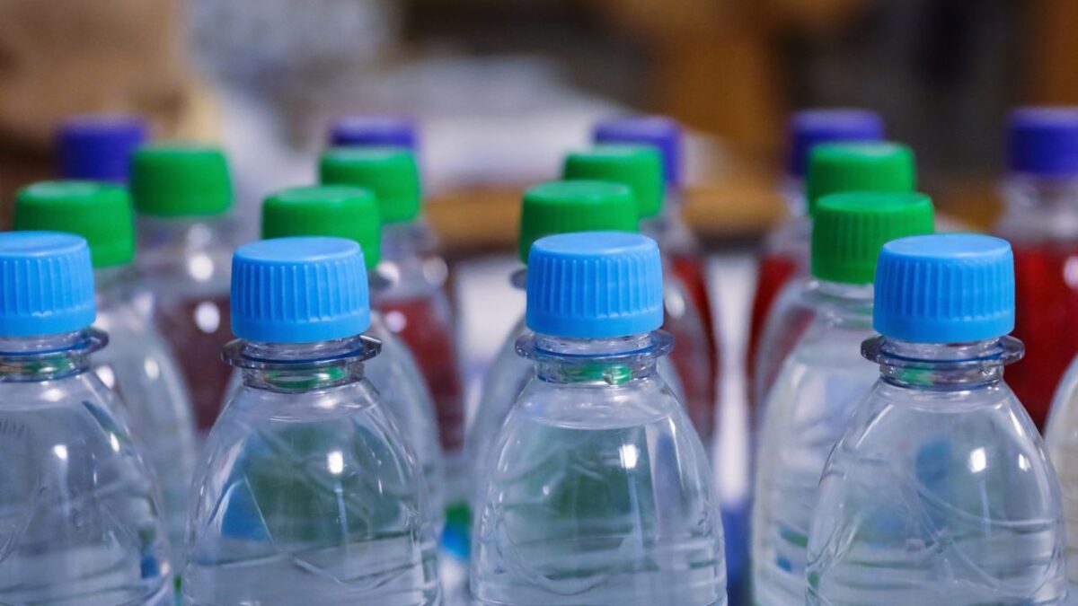 Many blue, green drinking water and refreshment beverage bottle caps and pure drinking water bottles in a drinking water production plant or supermarket shelf raw and lines. Close up. Selective focus