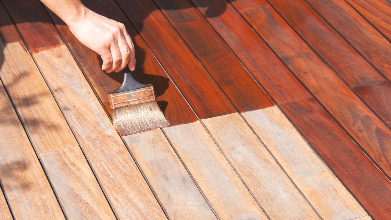 Exterior wood deck renovation, annual refreshing, worker's hand is oiling terrace decking with a painting brush after sanding