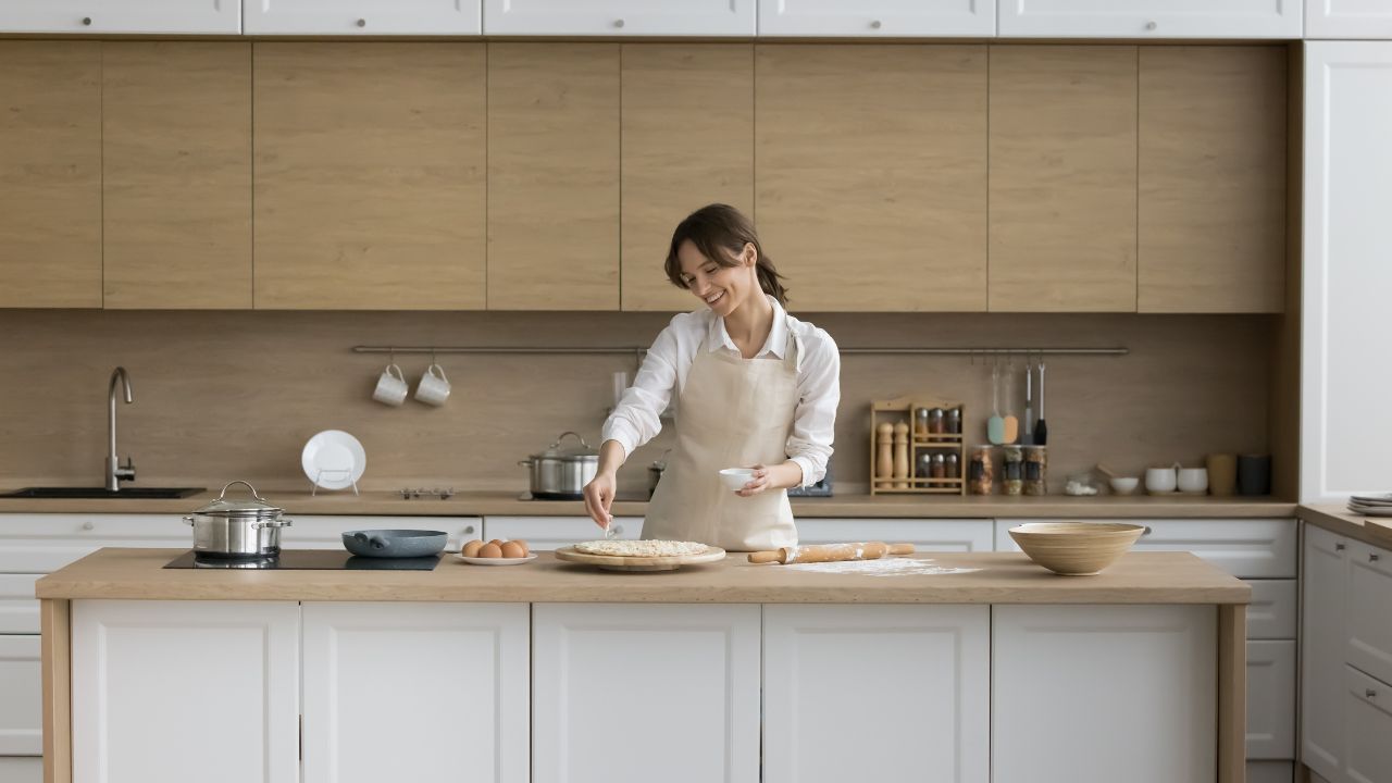 Young female wear apron cooking pizza, sprinkle dish with cheese, enjoy cooking in modern cozy kitchen, prepare Italian cuisine from natural ingredients on weekend at home, homemade cookery, chores
