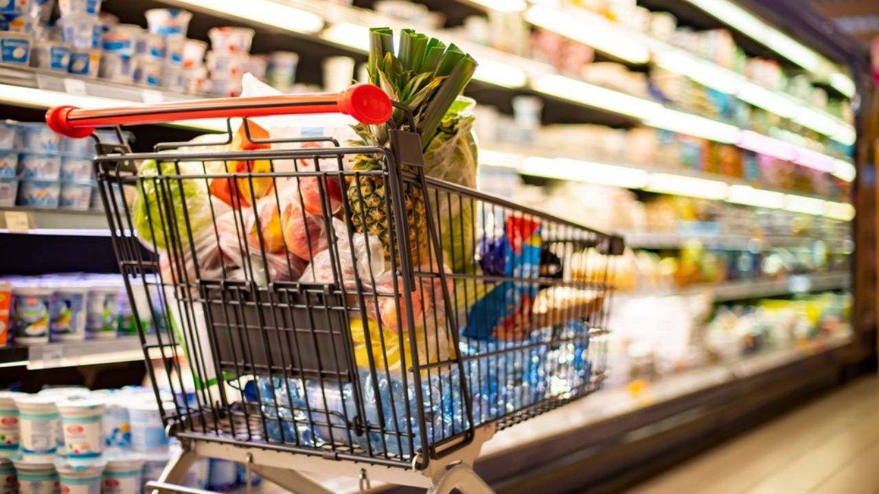 A shopping cart with grocery products in a supermarket
