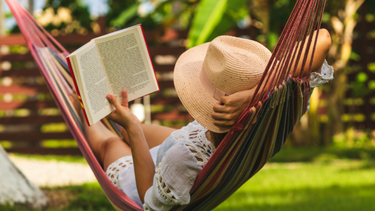 woman relaxing in a hammock reading a book in the backyard