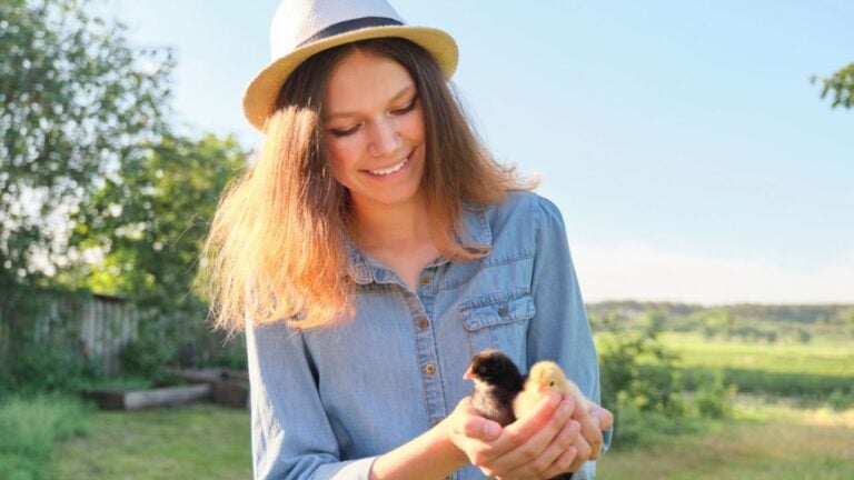 woman holding baby chicks chicken farming fedora hat farm