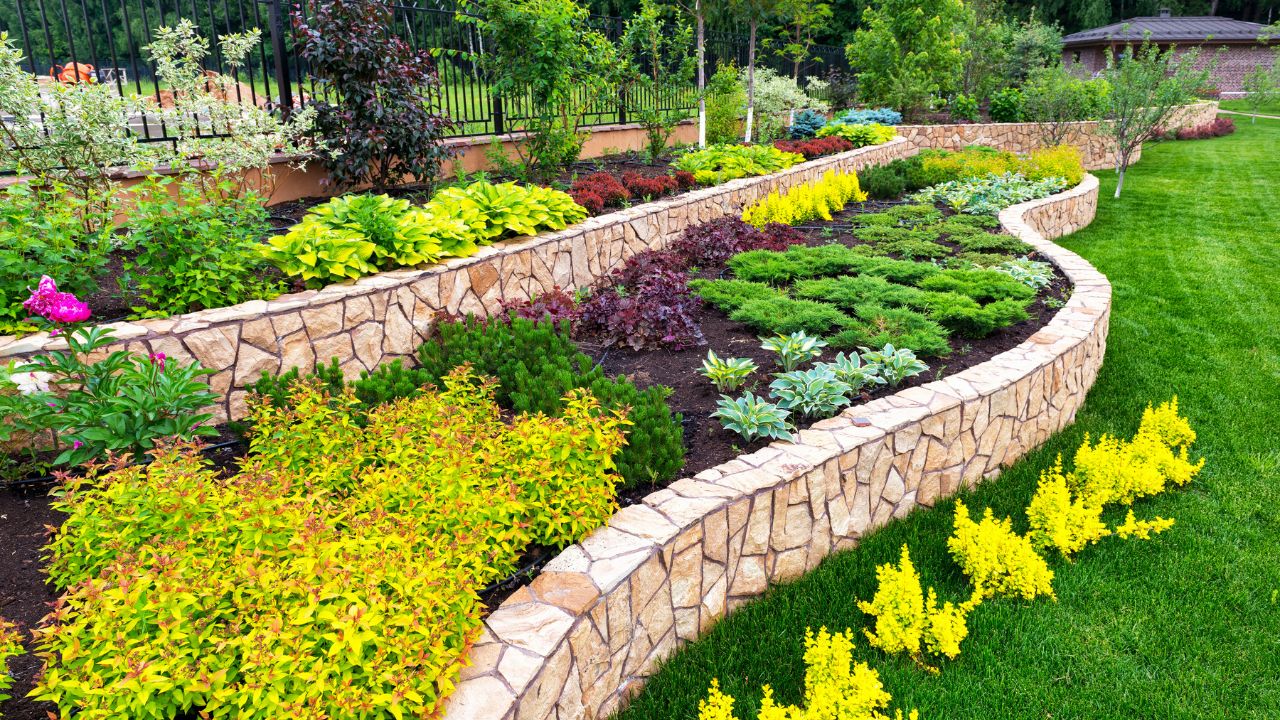 Landscape design of nice home garden, natural landscaping with decorative stones in residential house backyard. Luxury flowerbed and beautiful plants in summer, green upscale landscaped back yard.