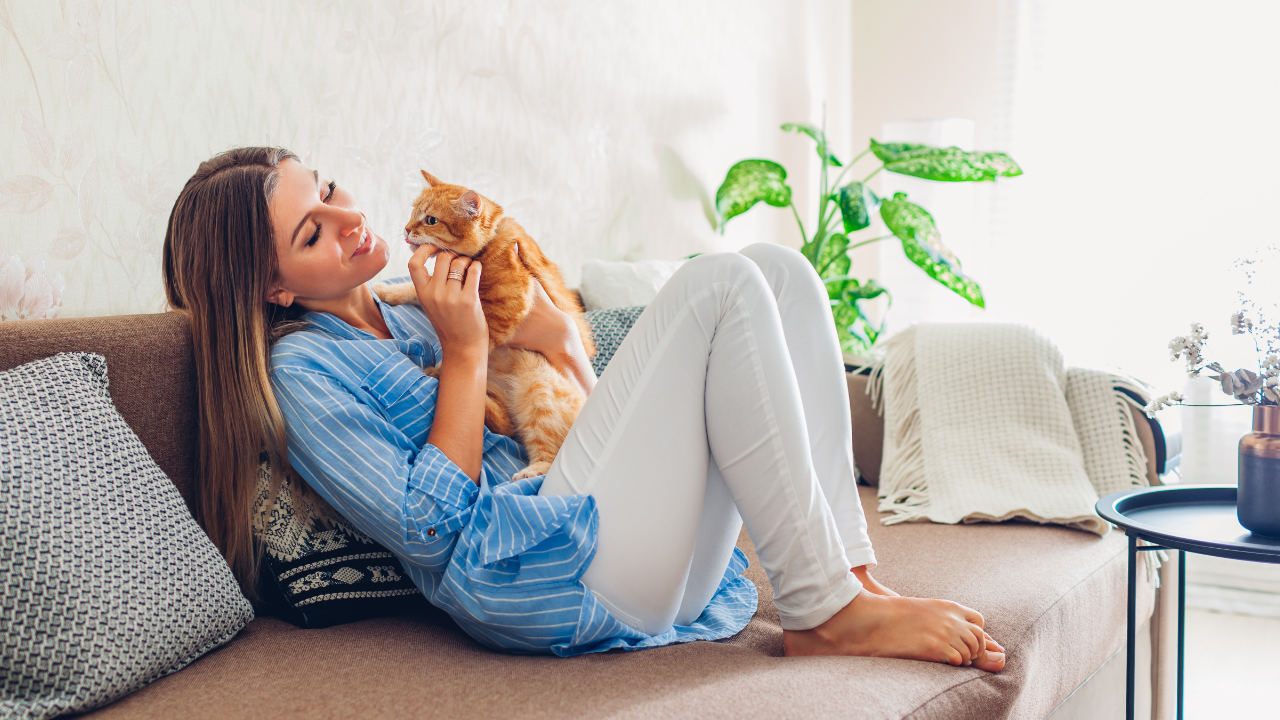 Woman playing with her cat surrounded by plants