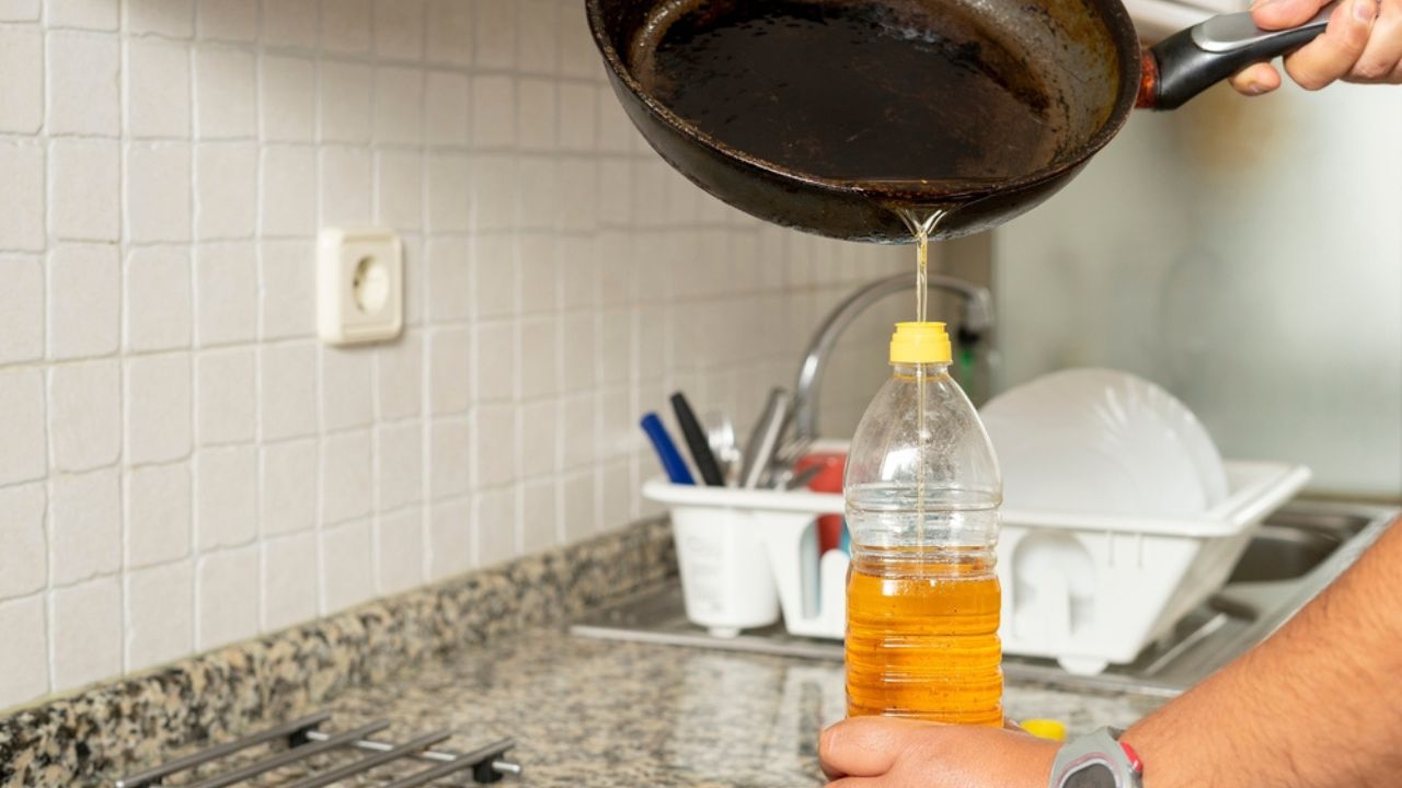 Man placing recycled edible oil from a frying pan into a plastic bottle in his home kitchen. Recycle at home concept. High quality photo