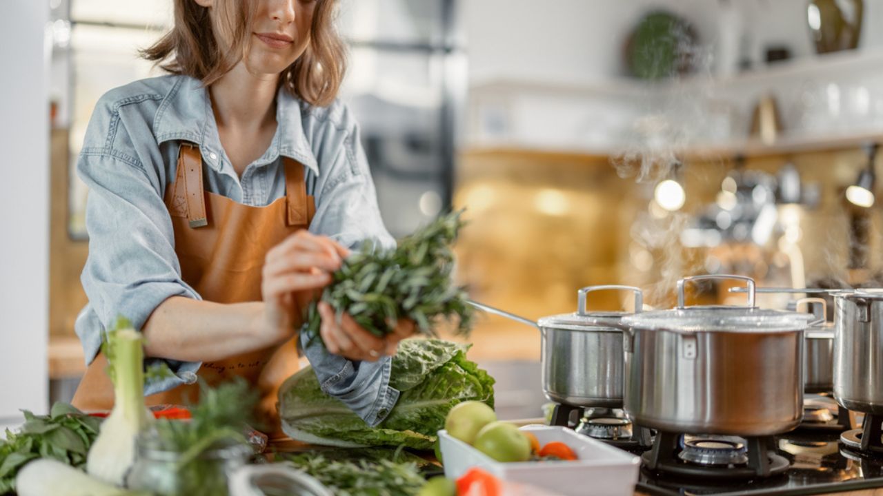 Pretty woman with green ingredients and spicy herbs cooking healthy food on the kitchen. Healthy and wellness concept. High quality photo
