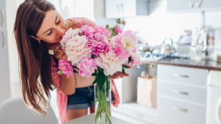 woman smelling a bouquet of flowers in a vase white kitchen