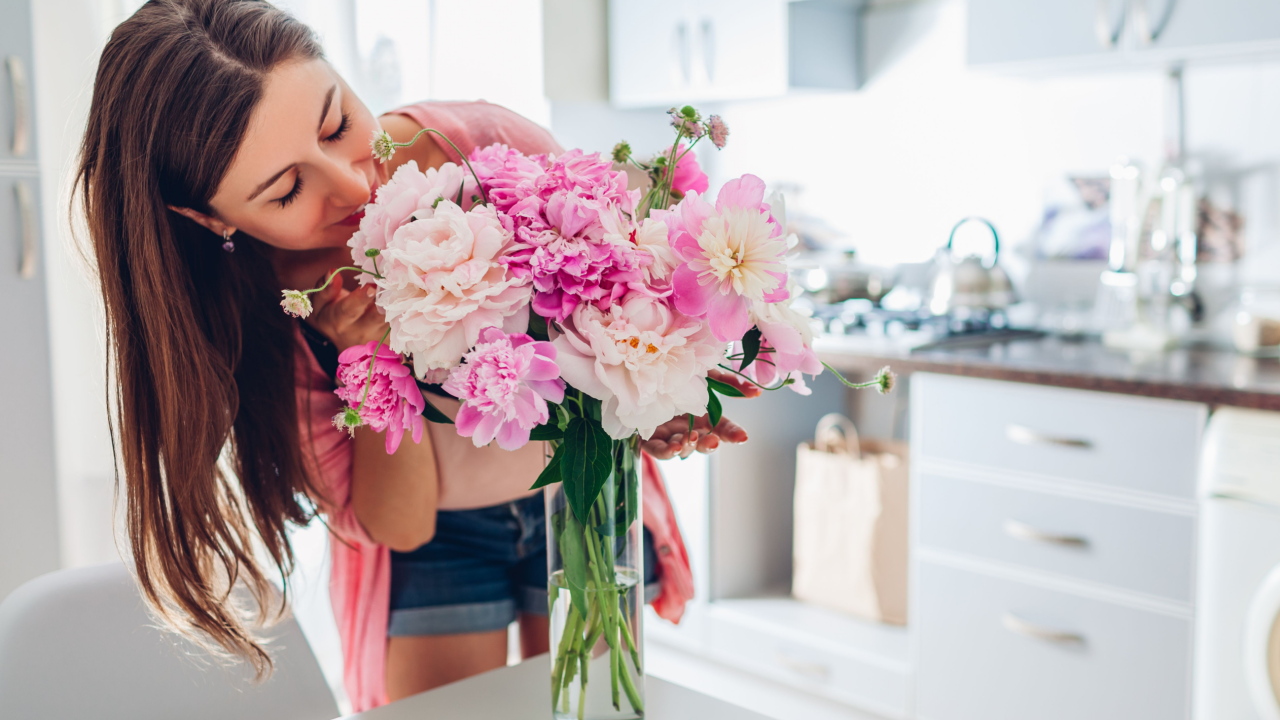 woman smelling a bouquet of flowers in a vase white kitchen