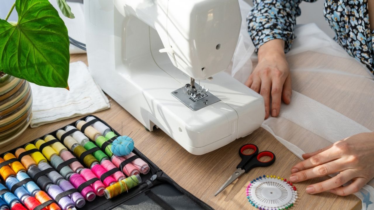 Woman hand close up sews tulle on electric sewing machine. Filling the thread into the sewing needle, adjusting the tension. Comfort in the house, a housewife's hobby, layout of sewing tools