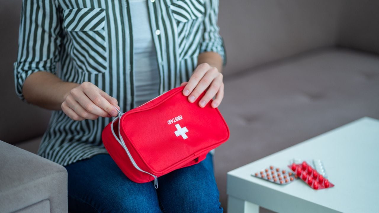 A Woman Holds a Medical First Aid Kit with Medicine at Home