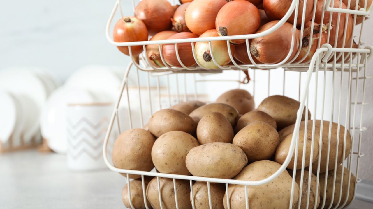 Container with potatoes and onions on grey kitchen counter. Orderly storage