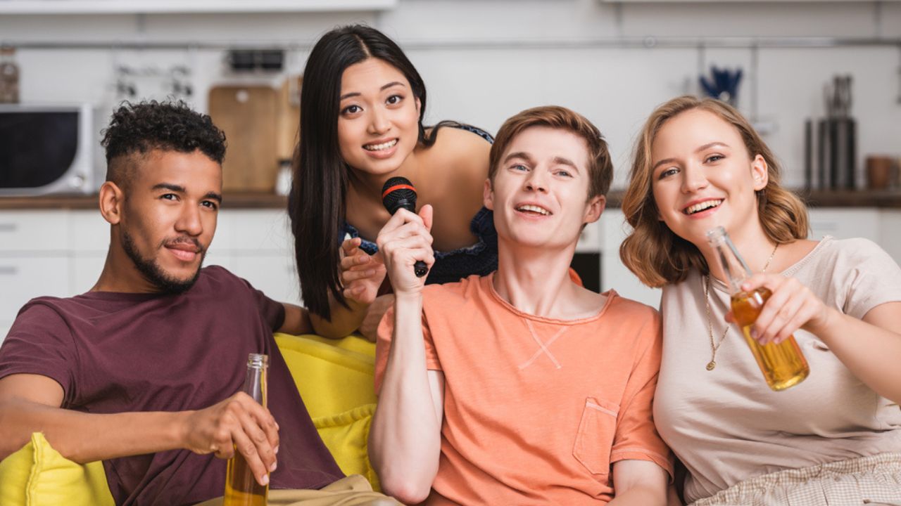 Joyful multicultural friends singing karaoke during party