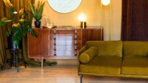 Living room with furniture. Retro Edison light bulbs. Mid century room in home with modern interior design, green velvet sofa, wooden cabinet, mirror