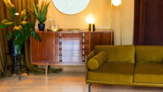 Living room with furniture. Retro Edison light bulbs. Mid century room in home with modern interior design, green velvet sofa, wooden cabinet, mirror