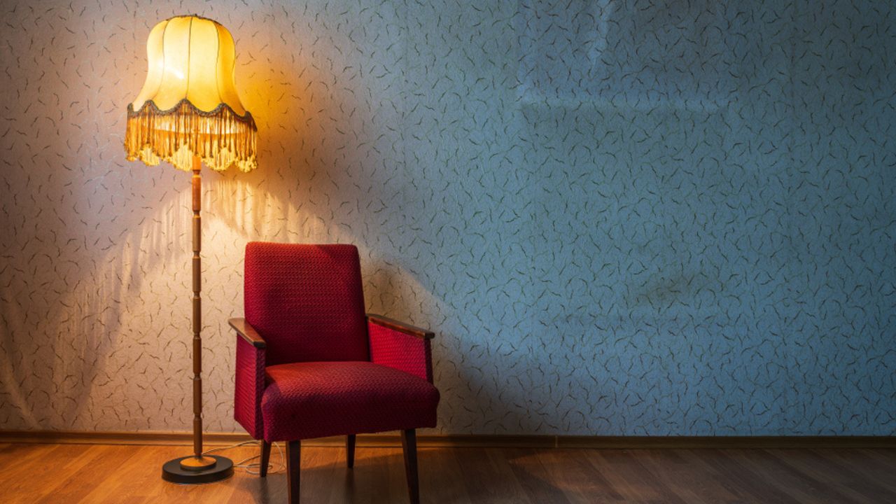 Old floor lamp and old armchair in a room.