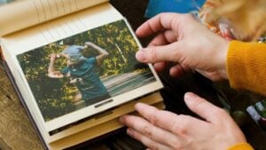 Photo printing. Young woman adding printed photo to family picture album.