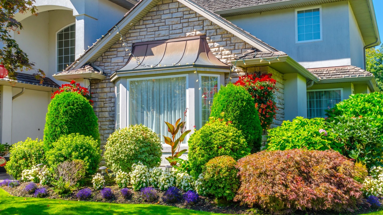 Big custom made luxury house with nicely landscaped and trimmed front yard and driveway to garage. Fragment.