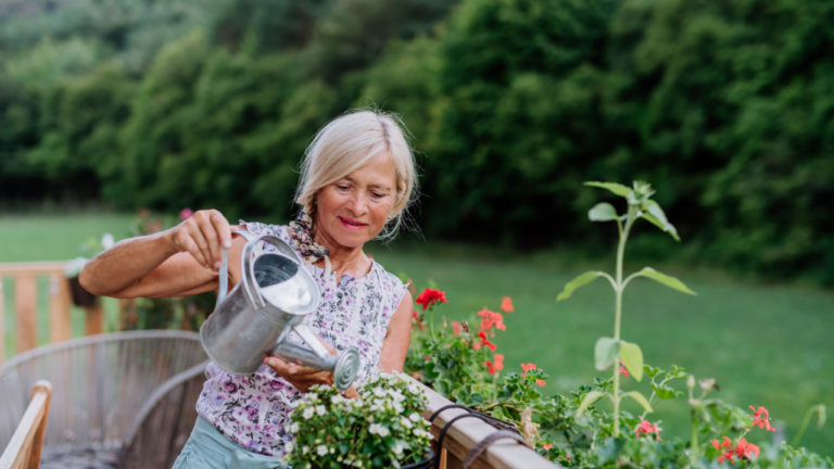 old woman watering flowers on her balcony