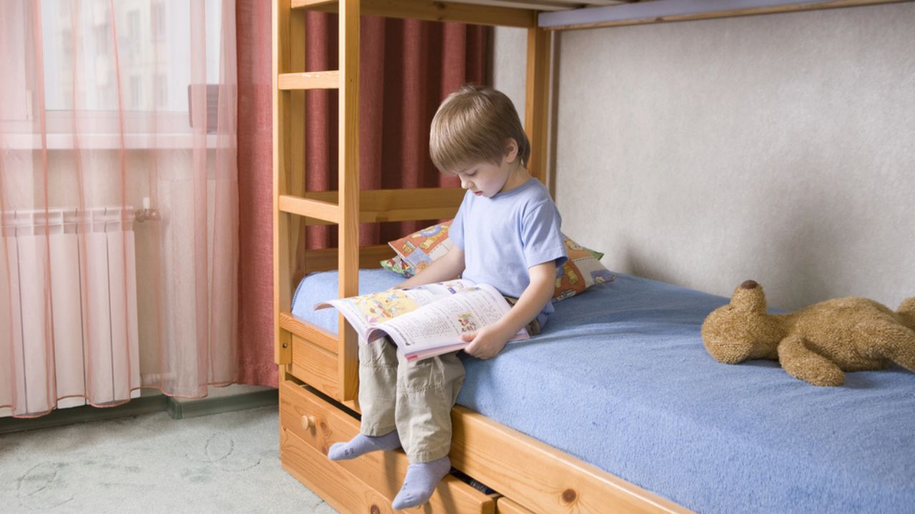 5 year old boy sits on bunk bed reading a book