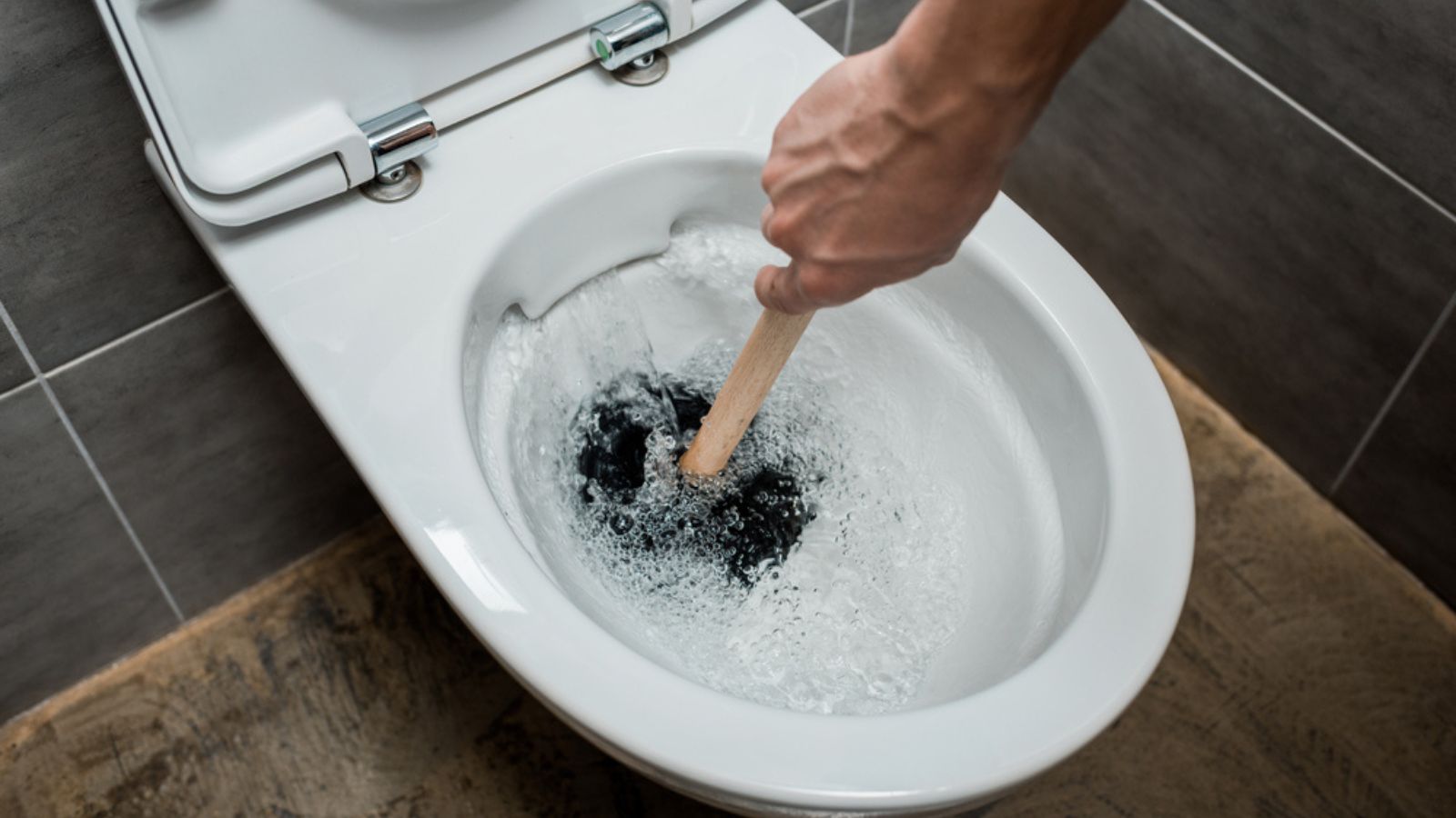 A man opening blocked Toilet using a wooden stick